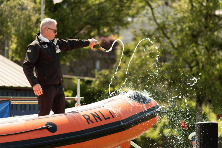 Champagne is poured over the bow of the lifeboat to officially name it.