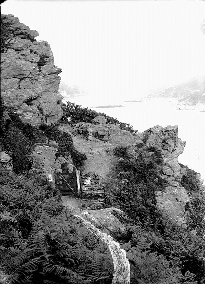 'Pathway to Bolt Head'. Looking back up the estuary, with the Blackstone etc. dimly seen in background. 
Gate in foreground. Yellow paint on plate forms waterfall-shaped mark in foreground.