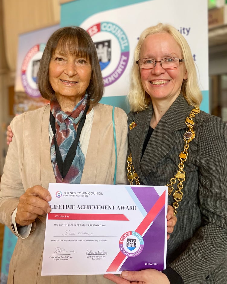 Cllr Emily Price with Sue Holmes, who received the Totnes Town Council Lifetime Achievement Community Award in 2024. Sue was nominated for an individual community award for her central role at Leechwell Garden Association.
In recognition of the exceptional length of service and her dedication, Town Councillors chose to give Sue a very special Lifetime Achievement Award.