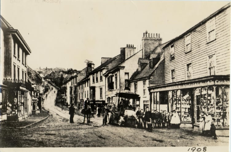 1908 An early bus parked in Modbury outside Trinick stationer, printer and cycle agent.