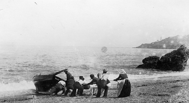 Men and women hauling  fishing boat 'Violet' up the beach at Hallsands