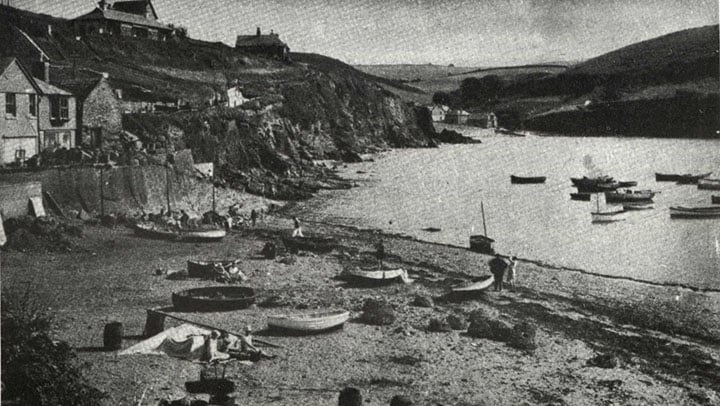 View towards Inner Hope from the beach at Outer Hope. Small boats on the beach and moored just offshore. 