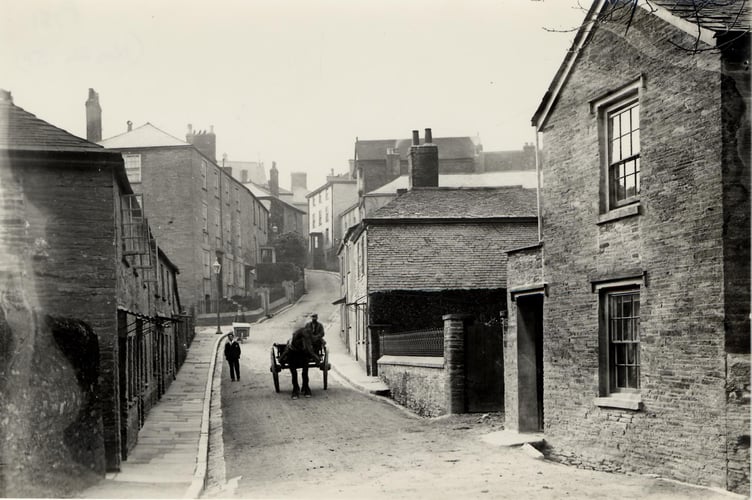 Duncombe Street, Kingsbridge, looking west to Fore Street. Man with wheelbarrow in background. Horses and cart coming down the hill